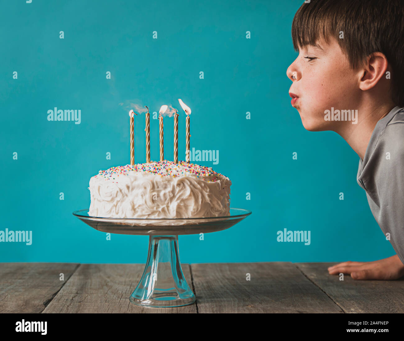 Junge ausblasen Kerzen auf der Geburtstagstorte vor blauem Hintergrund. Stockfoto
