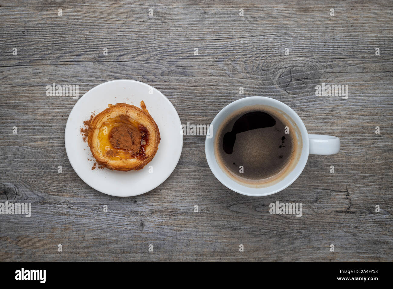 Traditionelle portugiesische Pastel de Nata Tarte mit einer Tasse schwarzen Kaffee auf einem Holztisch Stockfoto
