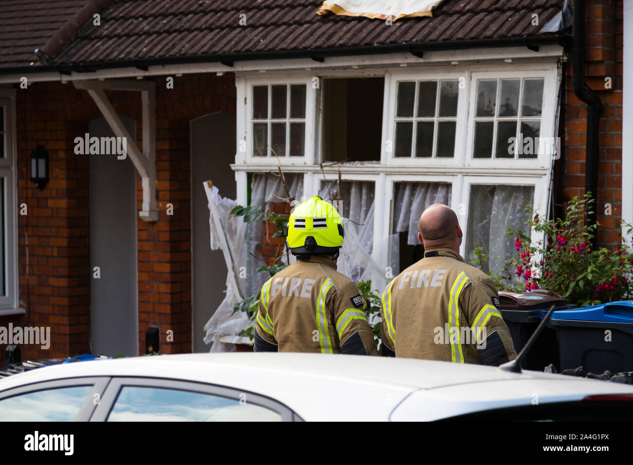 Zwei Feuerwehrmänner Blick auf eine beschädigte Satz vordere Windows nach einer großen gasexplosion auf Foxley Gärten, eine Straße mit Reihenhäusern im Süden Londons. Das Haus Stockfoto