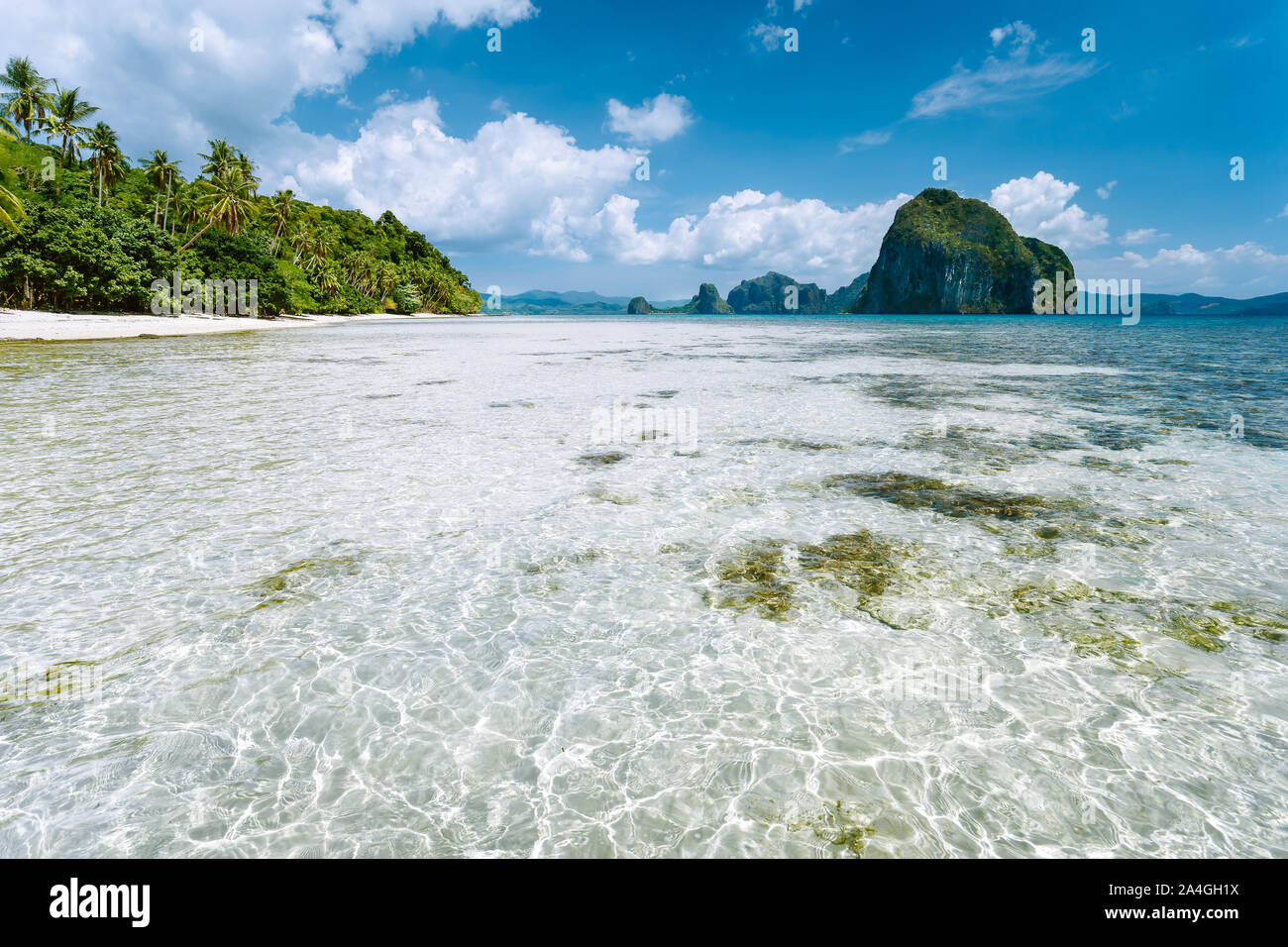 El Nido, Palawan, Philippinen. Flache Lagune, Sandstrand mit Palmen und erstaunliche Pinagbuyutan Insel im Hintergrund Stockfoto