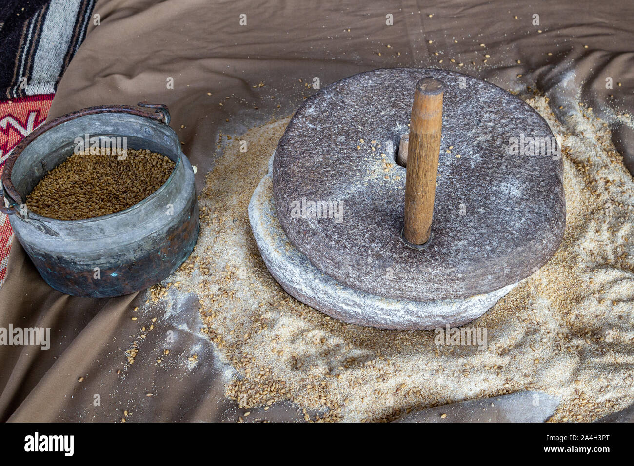 Schleifen Weizen von Hand in Stone Mill Stockfoto