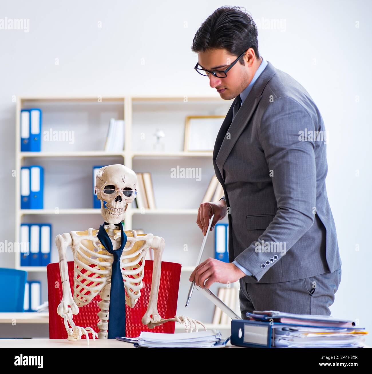 Der Geschäftsmann arbeiten mit Skelett im Büro Stockfoto