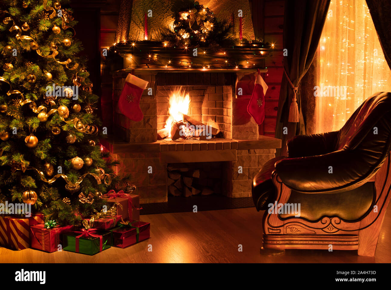 Weihnachten eingerichtetes Wohnzimmer mit Kamin, Sessel, Fenster und Baum Stockfoto