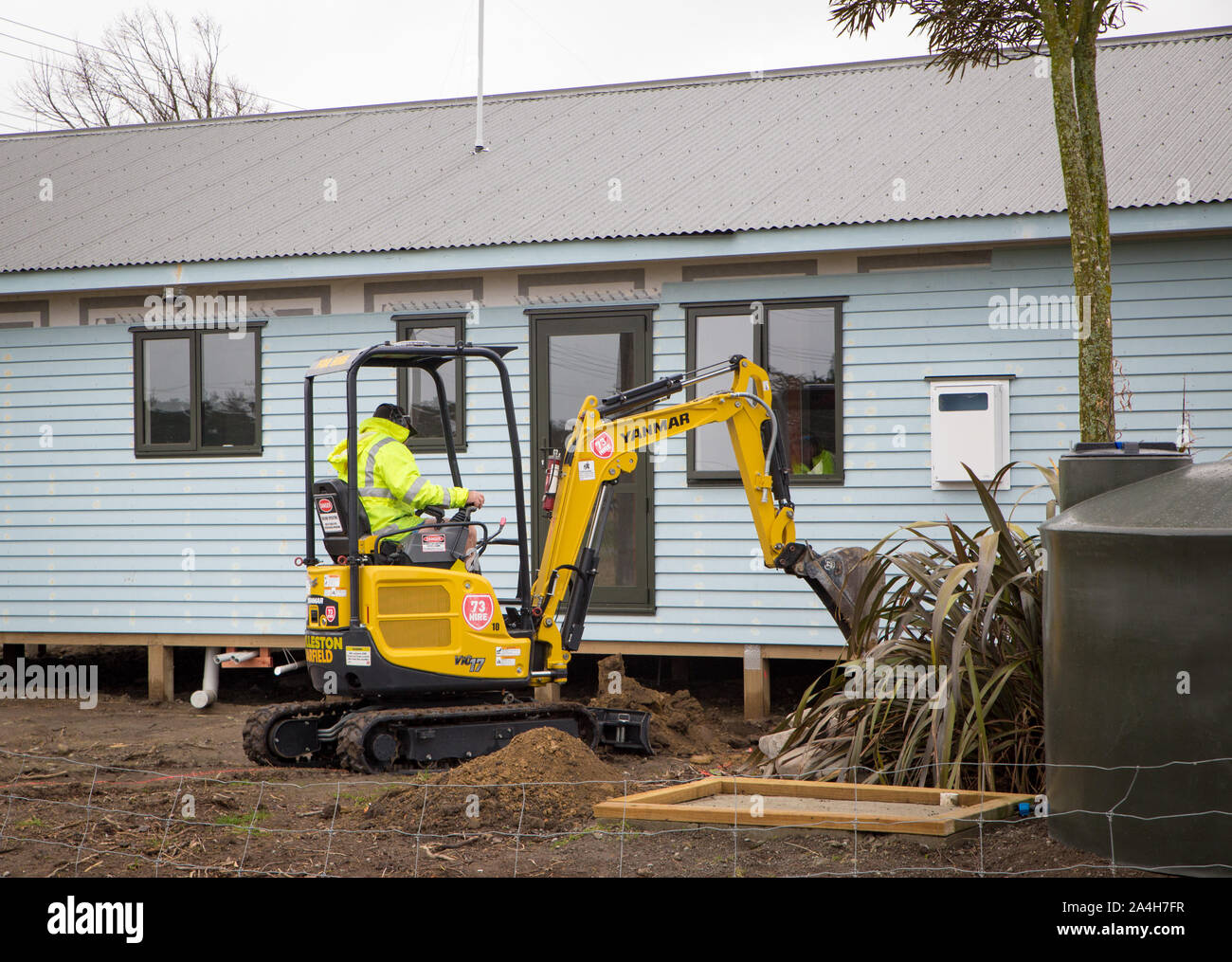 Ein Erbauer gräbt ein Graben auf einer Baustelle, die Wasser- und Stromversorgung Kabel in Canterbury, Neuseeland zu legen Stockfoto
