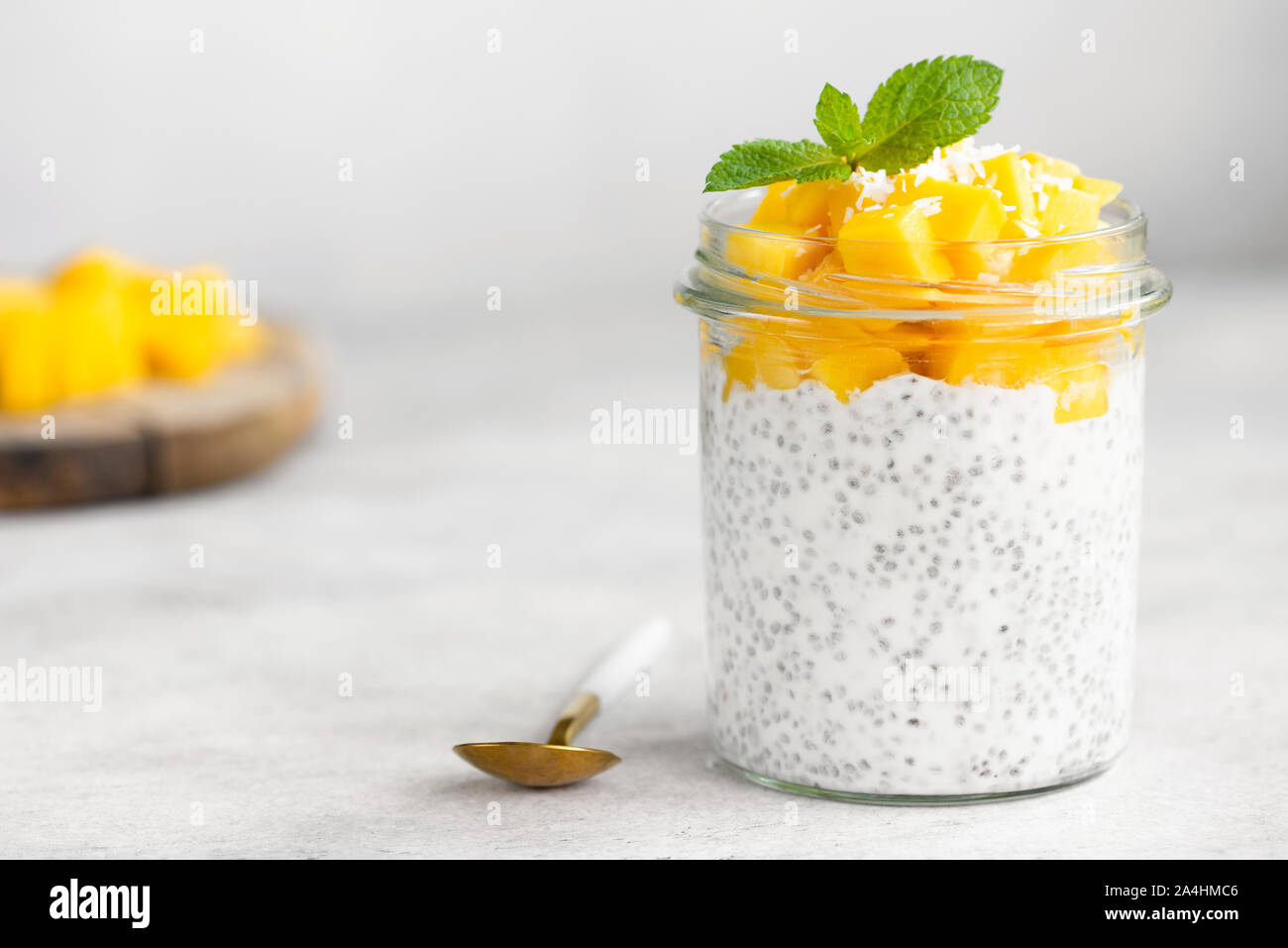 Chia Pudding mit Mango in den jar auf grauem Beton Hintergrund. Saubere Konzept Essen, gesunde vegetarische Kost Stockfoto