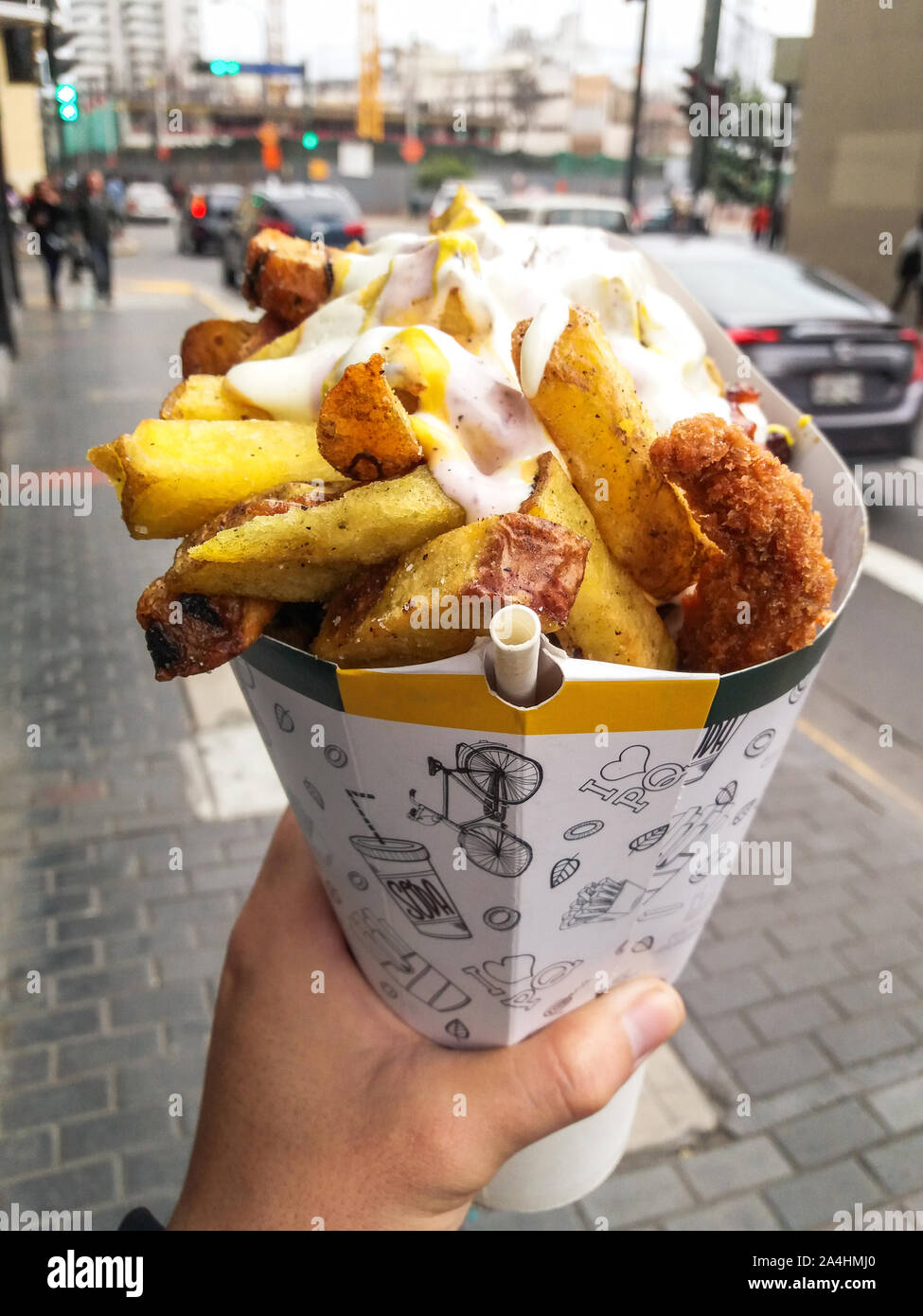 Schnelle Street Food in Lima - Peru, Pommes frites und gebratenes Huhn mit Mayonnaise unter anderen Cremes in einem Kegel Stockfoto