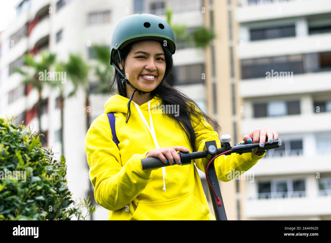 Lachende junge Frau mit Helm auf einem elektrischen scooter Stockfoto