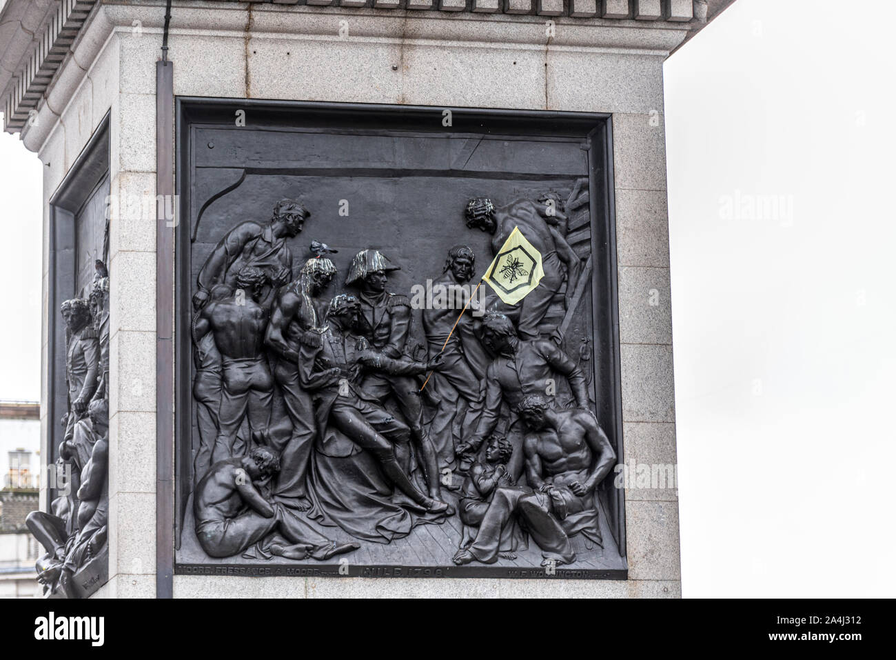 Aussterben Rebellion Morgendunst am Trafalgar Square, London, UK. Protest Camp. Fahne Flagge auf Bronze Fries der Nelson's Column Stockfoto