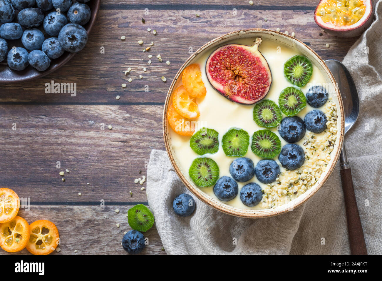 Einen frischen organischen Joghurt smoothie Schüssel mit einer Variation von frischen Früchten von oben gesehen - Heidelbeeren, Kiwis, Feigen, Passionsfrucht und kumquat und Stockfoto