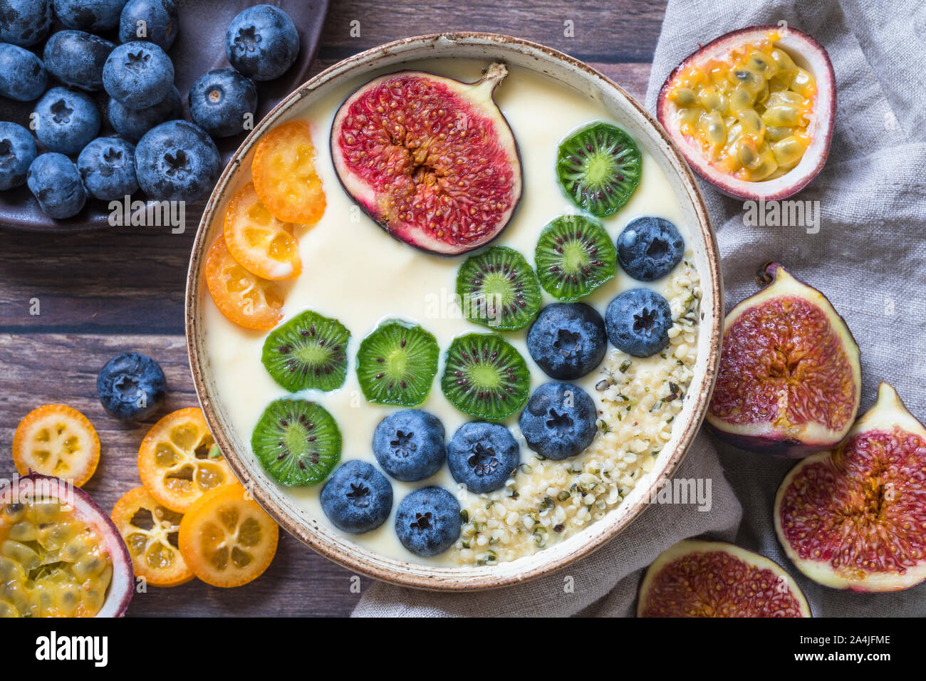 Einen frischen organischen Joghurt smoothie Schale von oben gesehen mit einer Variation von frischen Früchten - Heidelbeeren, Kiwis, Feigen, Passionsfrucht und kumquat. Einige Stockfoto