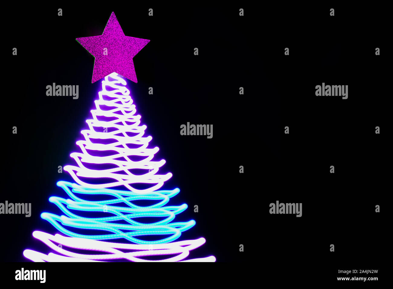 Weihnachtsbaum in Neon Pink und Blau freezelight Strahlen auf Schwarz. Kreative Muster mit Platz für Text und Urlaubswünsche. Xmas Party Hintergrund. Stockfoto