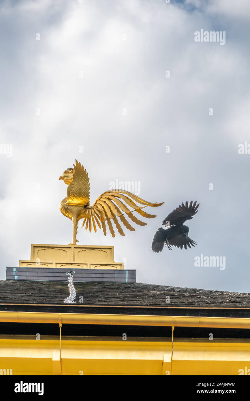 Crow flying hinter Bronze Phoenix - Garuda (O-ho) Ornament an der Spitze der shariden der Rokuon-ji Tempel, allgemein bekannt als die Goldene Pavillon Kinkakuji Stockfoto