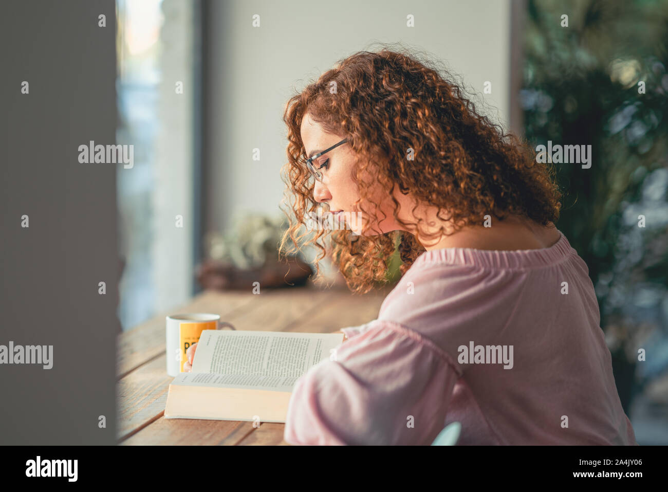 Junge Frau mit Brille Buch lesen im Cafe. Stockfoto