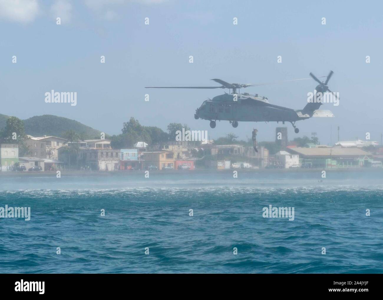 U.S. Navy Naval Aircrewman (Hubschrauber) 2. Klasse Benjamin Lazarus, der "Dragon Wale" von Hubschrauber Meer Combat Squadron 28 zugewiesen, angeschlossen an das Krankenhaus ship USNS Comfort (T-AH 20), springt von einem MH-60S Seahawk während einer Suche und Rettung Demonstration vor der Küste von Basseterre, St. Kitts und Nevis, Okt. 11, 2019. Komfort ist das Arbeiten mit Gesundheit und Regierung Partner in Mittelamerika, Südamerika und die Karibik zu kümmern, auf dem Schiff und an Land-basierte medizinische Websites, wodurch der Druck auf die nationalen medizinischen Systemen, einschließlich derer, die durch eine Erhöhung der cros angespannt zu entlasten Stockfoto