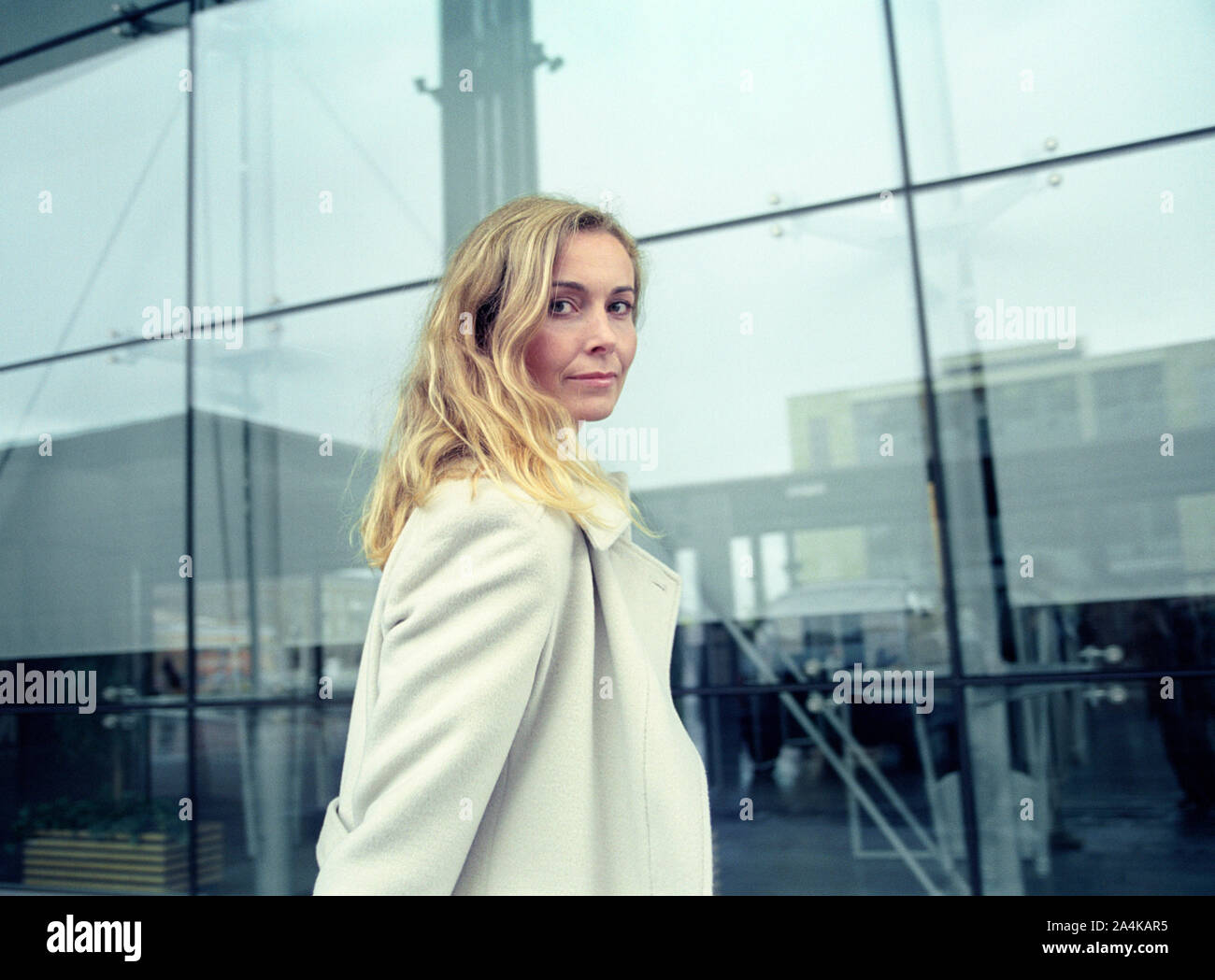 Blonde Frau trug einen Mantel Stockfoto