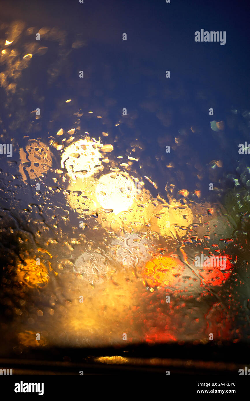 Verkehr in der Nacht. Licht und Wasser Tropfen durch Auto Fenster gesehen. Stockfoto