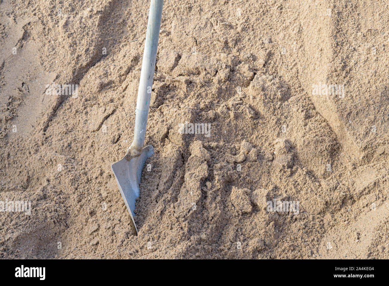 Ein Spaten steht in einem Haufen Sand auf einem Bauvorhaben. Stockfoto