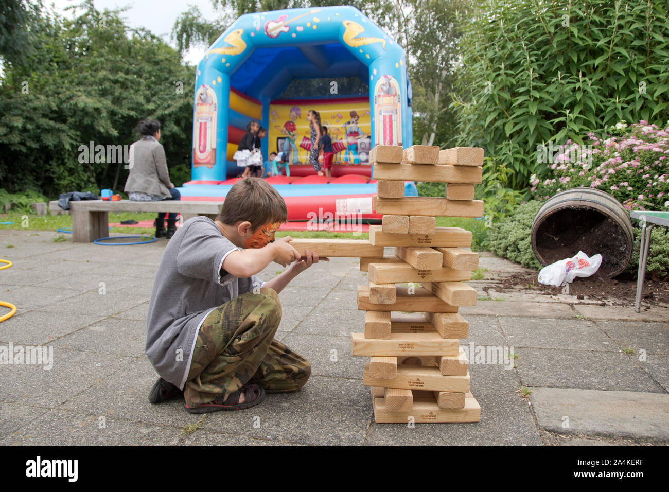 Sheffield, Großbritannien: 1 Aug 2016: Ein kleiner Junge spielen Riesen Jenga mit einem timebuilders Volontär an der St. Mary's Kirche Familie Spaß-Tag Stockfoto