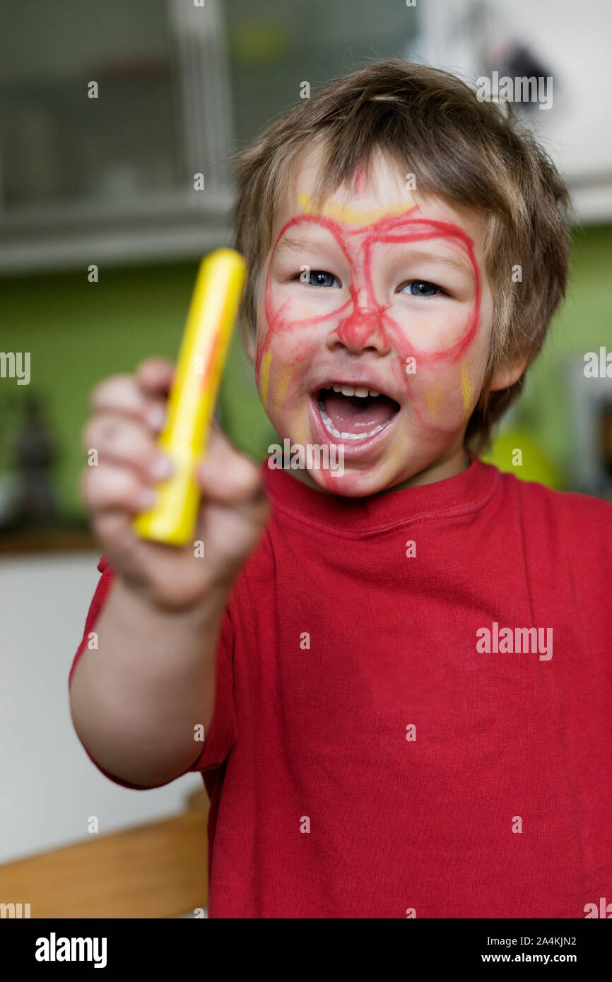 Junge Holding Zeichenstift mit bemaltem Gesicht Stockfoto