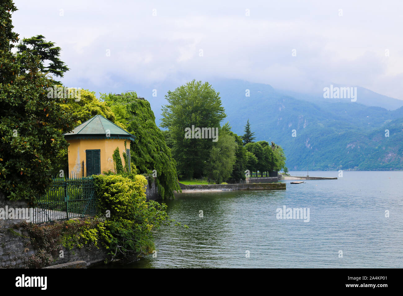 Zaun mit Efeu mit litle Gebäude in der Nähe des Comer See, Berg im Hintergrund. Stockfoto