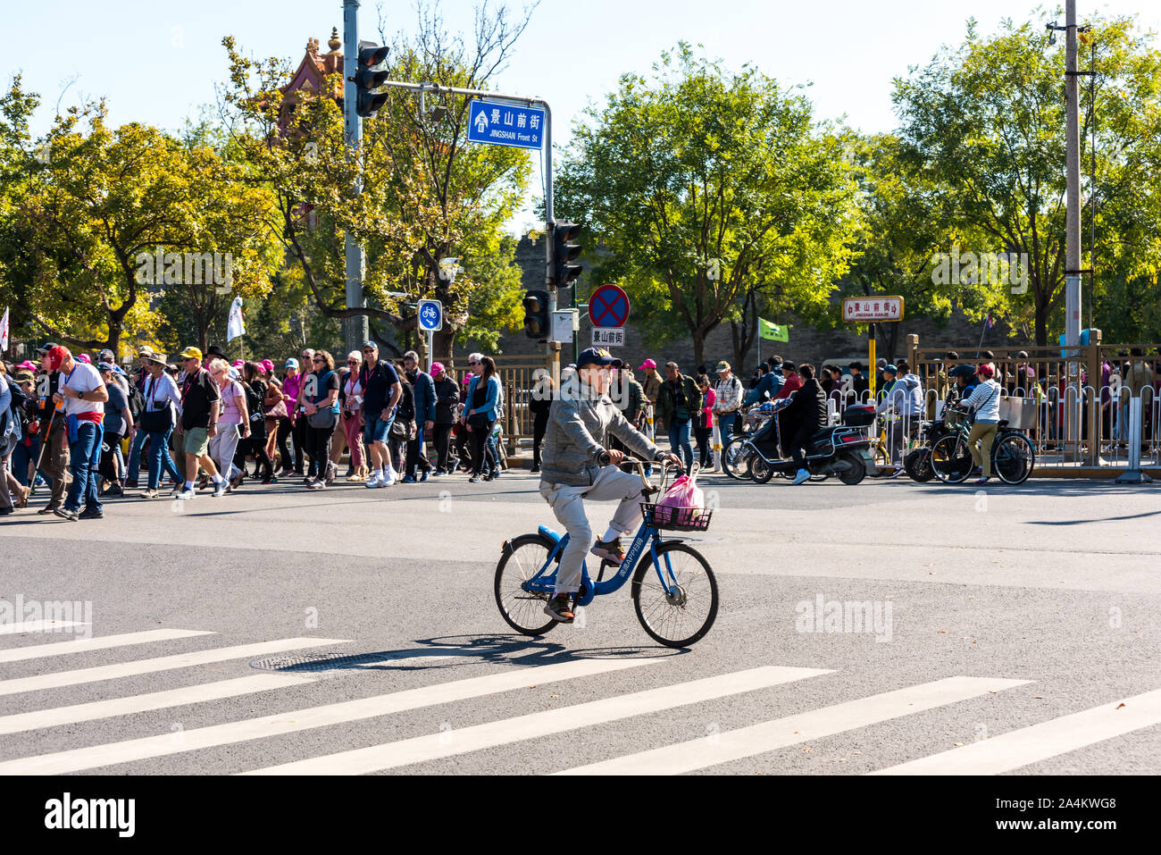 Ein Mann auf einem Fahrrad acrossing die Straße mit einer Menge Leute, in der Altstadt von Peking, China Stockfoto