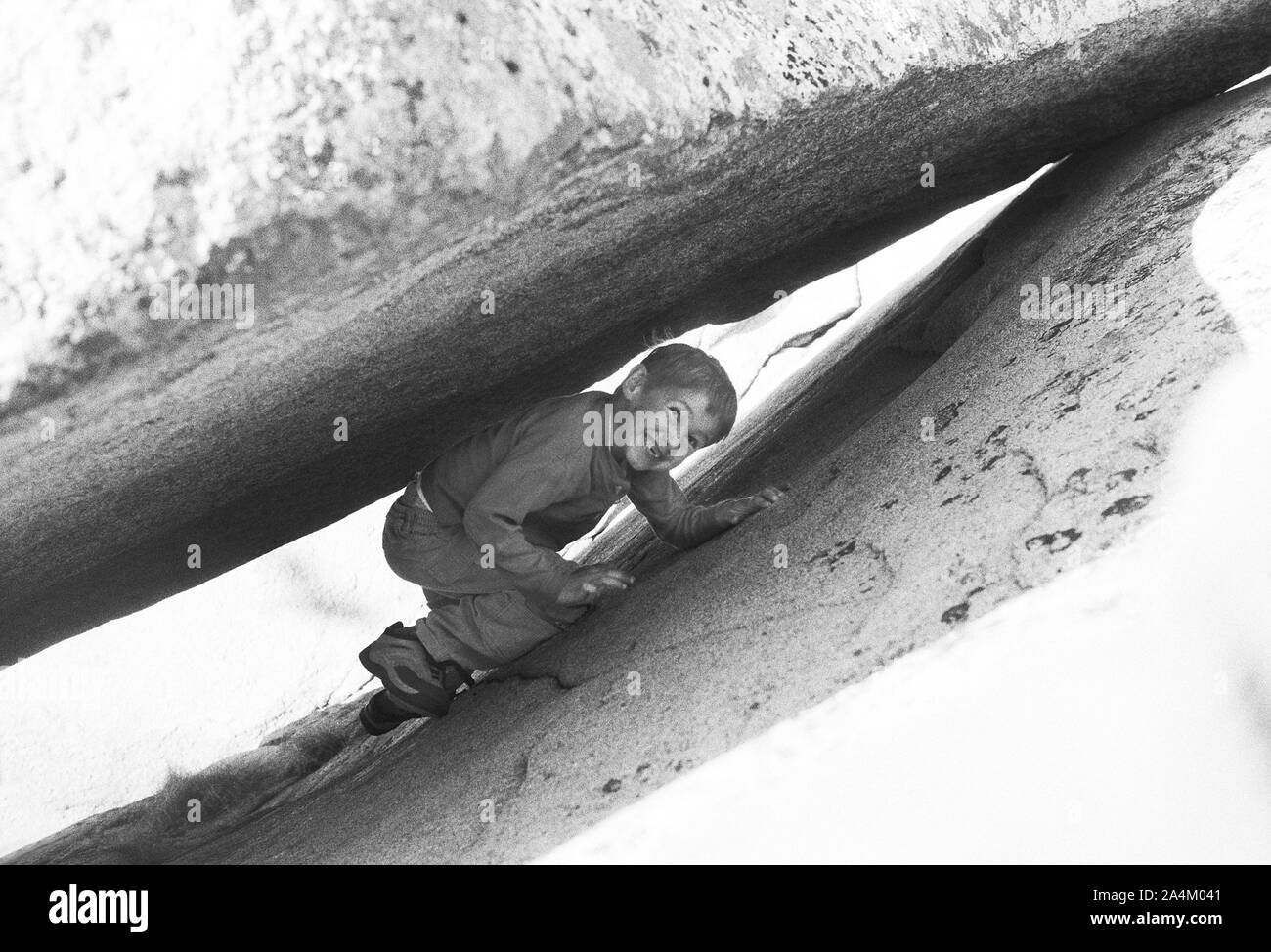 Junge versteckt sich unter rock Stockfoto