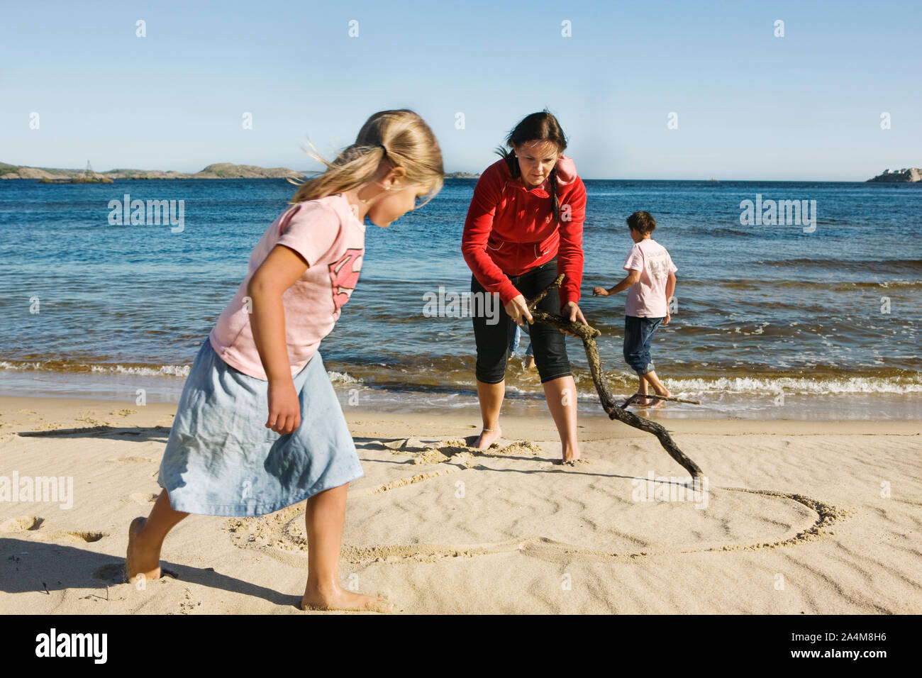 Eine Mutter zieht ein Herz im Sand, Norwegen Stockfoto