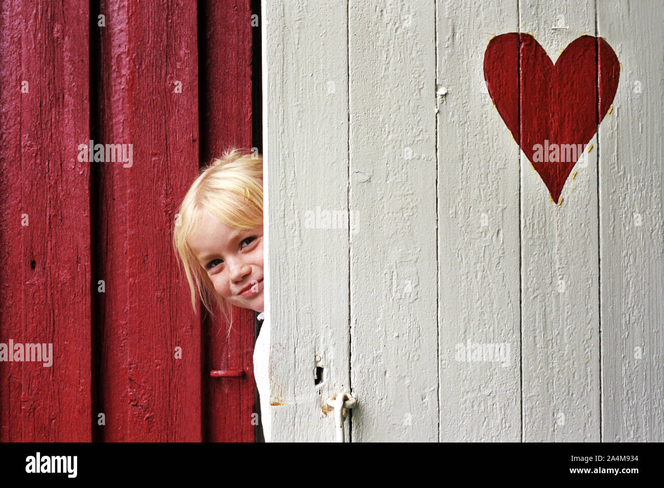 Mädchen aus dem WC-Tür mit einem gemalten Herzen - der Charme des Lebens in einer Kabine. Stockfoto