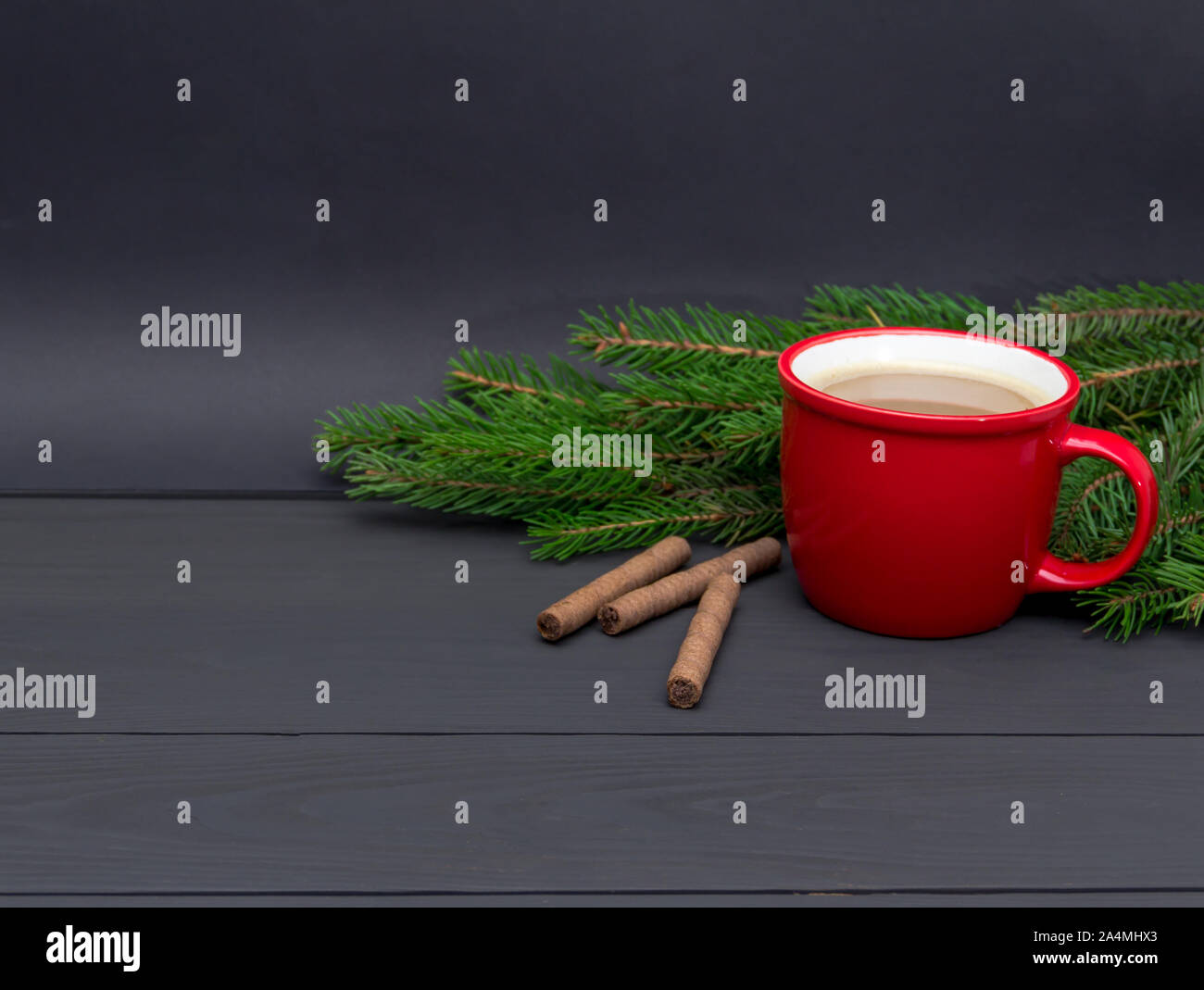 Rot Tasse Kaffee und Tannenzweigen auf dunklem Hintergrund. Weihnachten Konzept. Kostenlose Kopie. Stockfoto