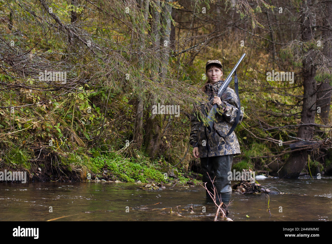 Frau Jäger in Camouflage mit Gewehr auf dem Fluss Stockfoto