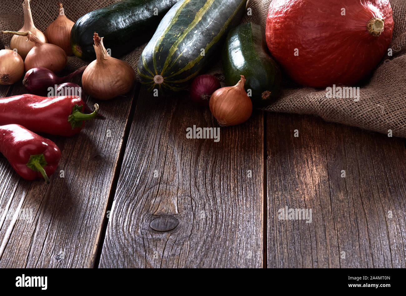 Noch immer leben auf der hölzernen Tischplatte. Kürbis mit Zucchini oder Gurken und Zwiebeln. Red Pepper auf Jute Tasche. Stockfoto