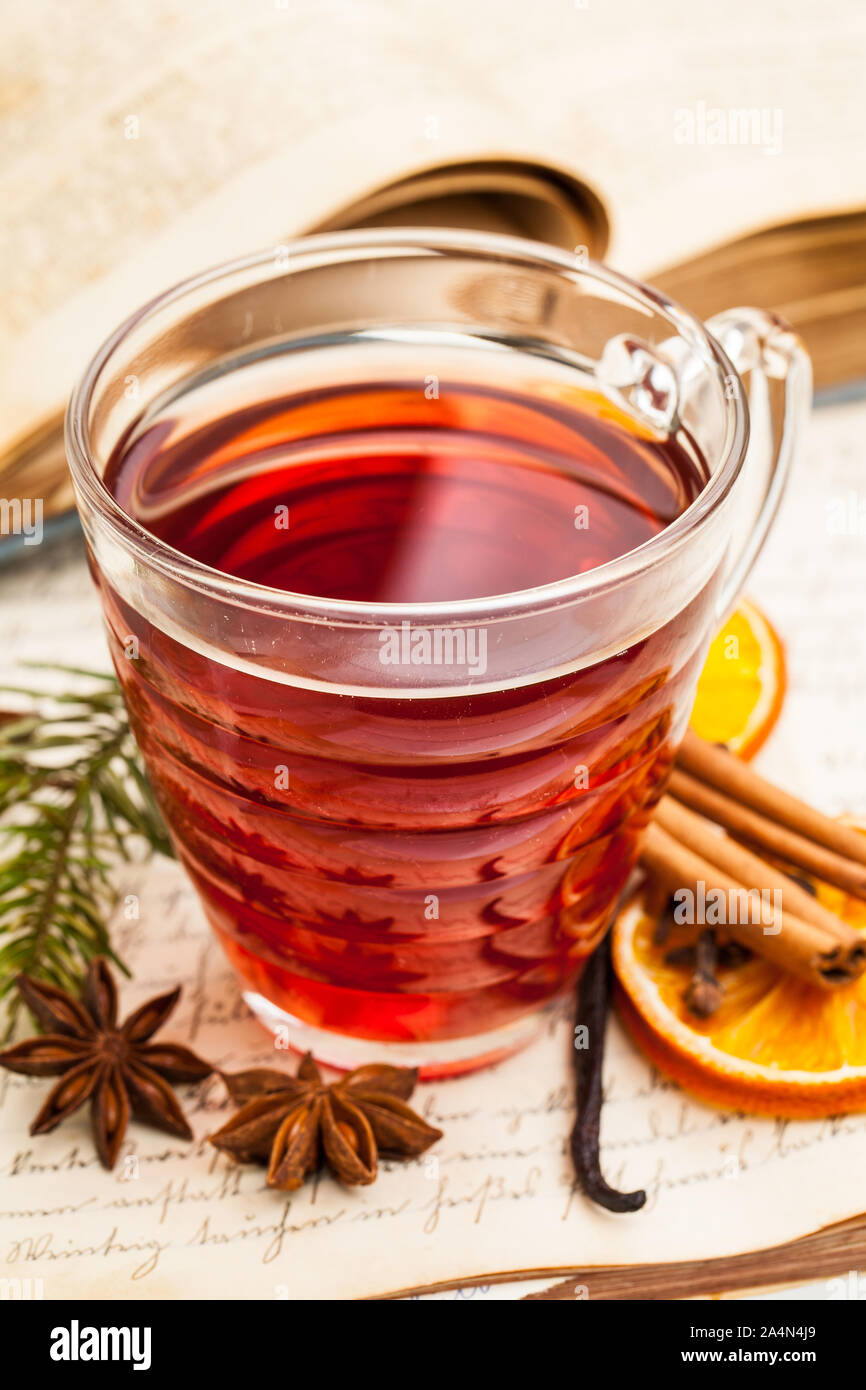 Glühwein mit Gewürzen auf einem alten Kochbuch Stockfoto
