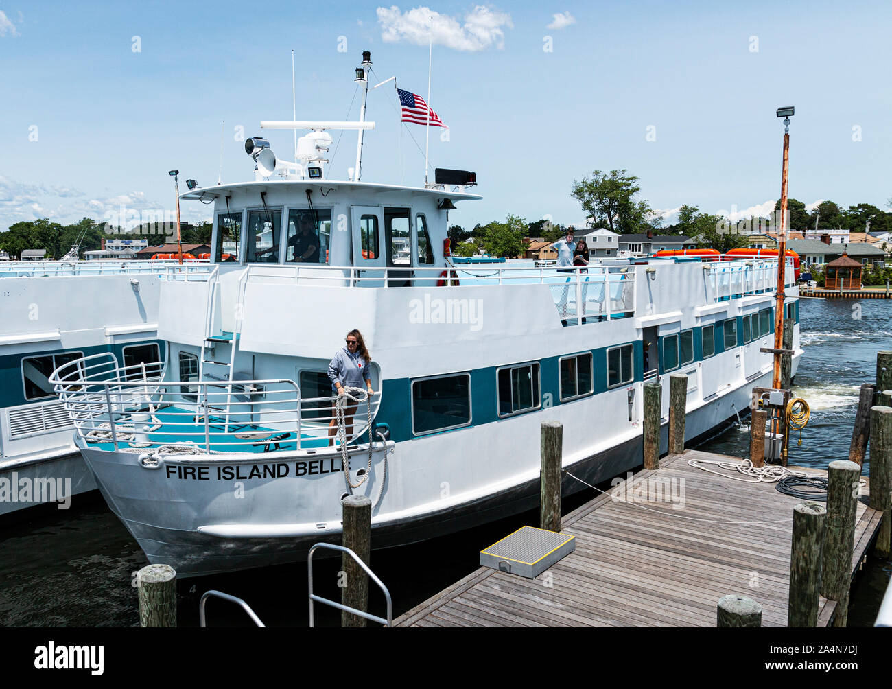 Bay Shore, New York, USA - 22. Juni 2019: Ein Arbeiter auf dem Fire Island Bell Fähre Schiff ist über ein Seil auf einer häufen, wie das Schiff wieder in die m zu werfen Stockfoto