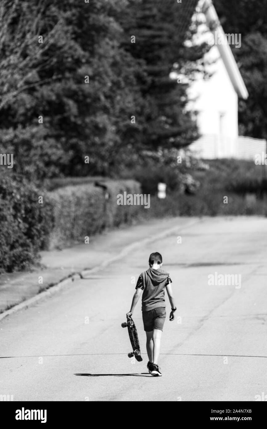 Junge mit Skateboard auf der Straße Stockfoto