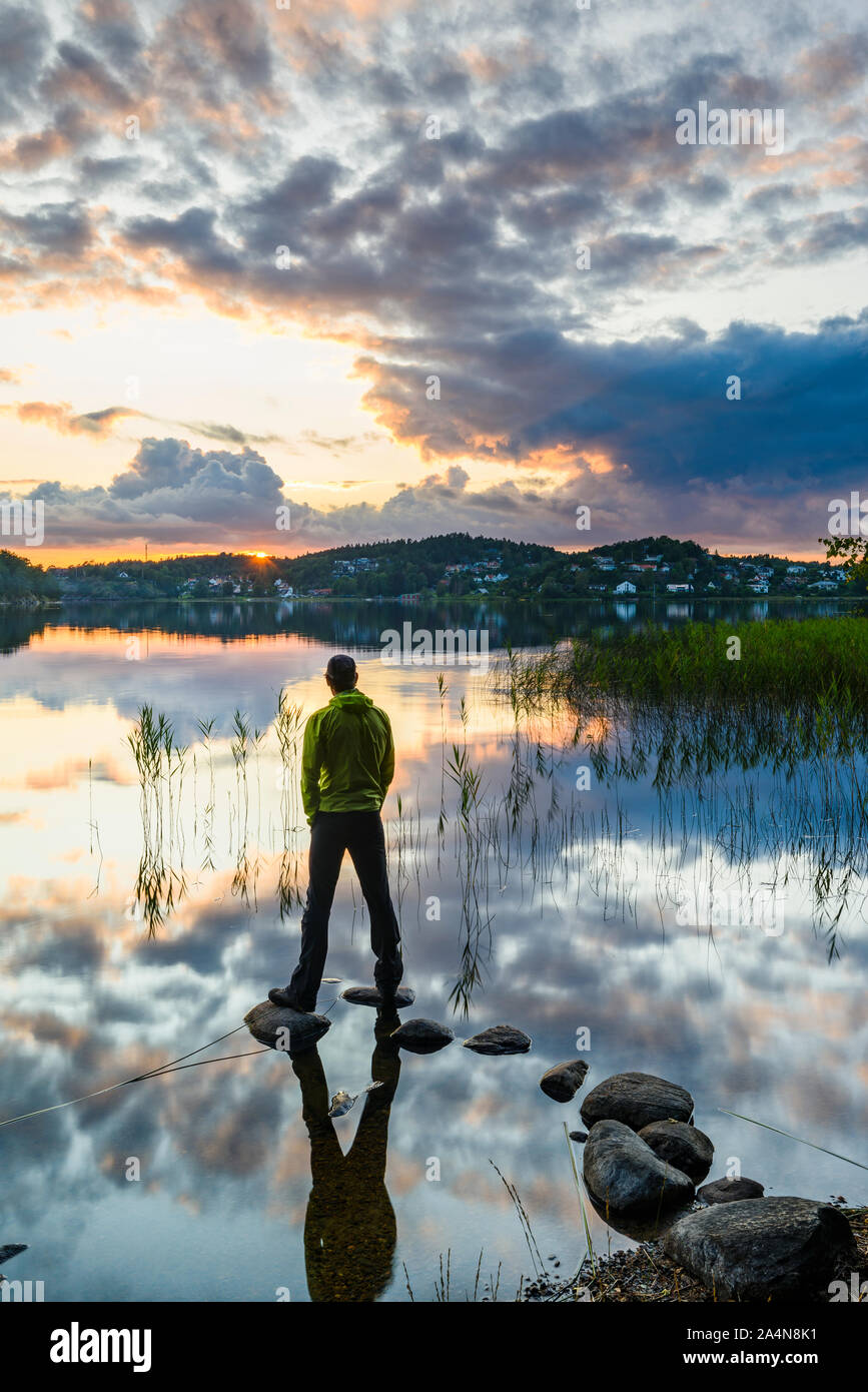 Mann stand am See bei Sonnenuntergang Stockfoto