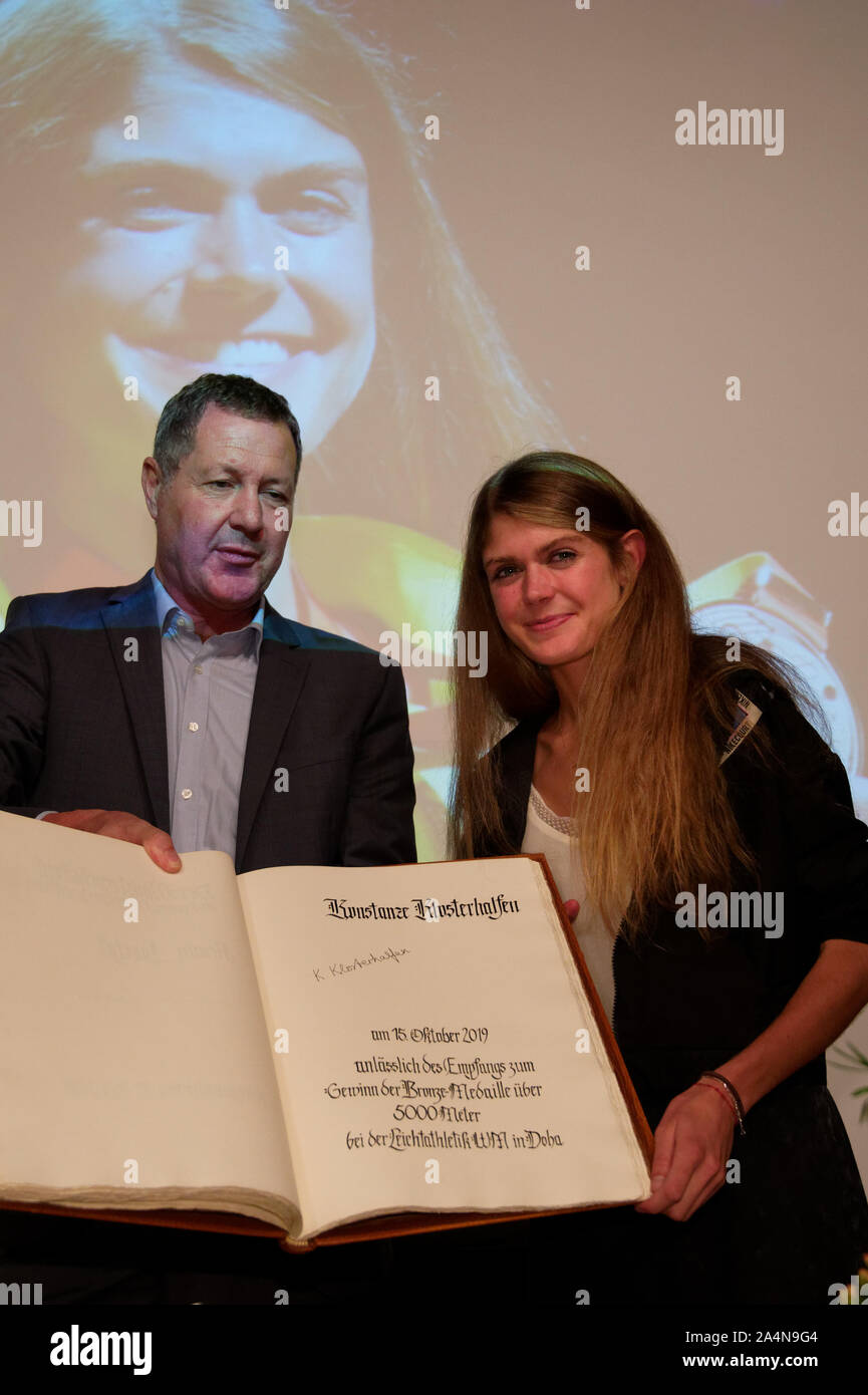 15. Oktober 2019, Nordrhein-Westfalen, Königswinter: Die sportlerin Konstanze Klosterhalfen (r) und der Bürgermeister Peter Wirtz (l, CDU) zeigte der Schriftzug auf einem Empfang anlässlich der Eintragung in das Goldene Buch der Stadt. Klosterhalfen gewann die Bronzemedaille im 5000-Meter-Lauf bei den Leichtathletik Weltmeisterschaften in Doha. Foto: Henning Kaiser/dpa Stockfoto