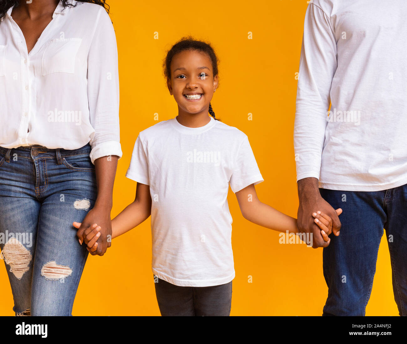 Cute afrikanische amerikanische Mädchen halten sich an den Händen ihrer Eltern Stockfoto