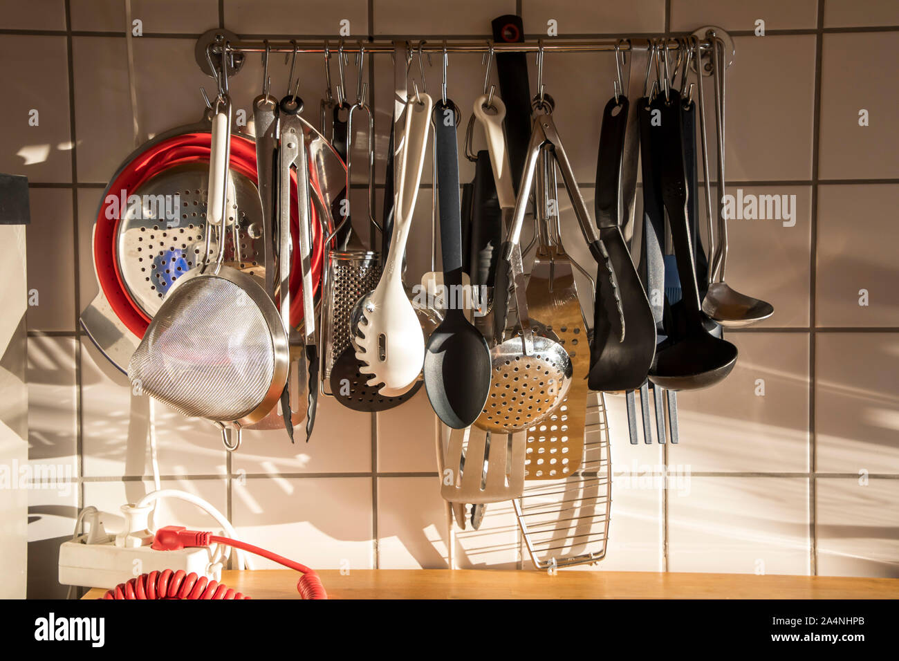 Diverse Küchengeräte, Schöpfkellen, Löffel, Siebe, Zangen, in einer eigenen Küche, Stockfoto
