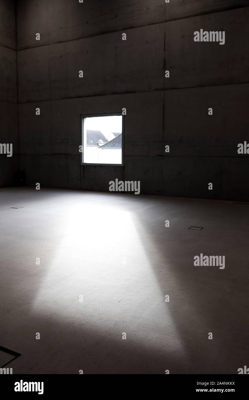 Licht fällt durch ein rechteckiges Fenster in einen großen, leeren Raum, Stockfoto