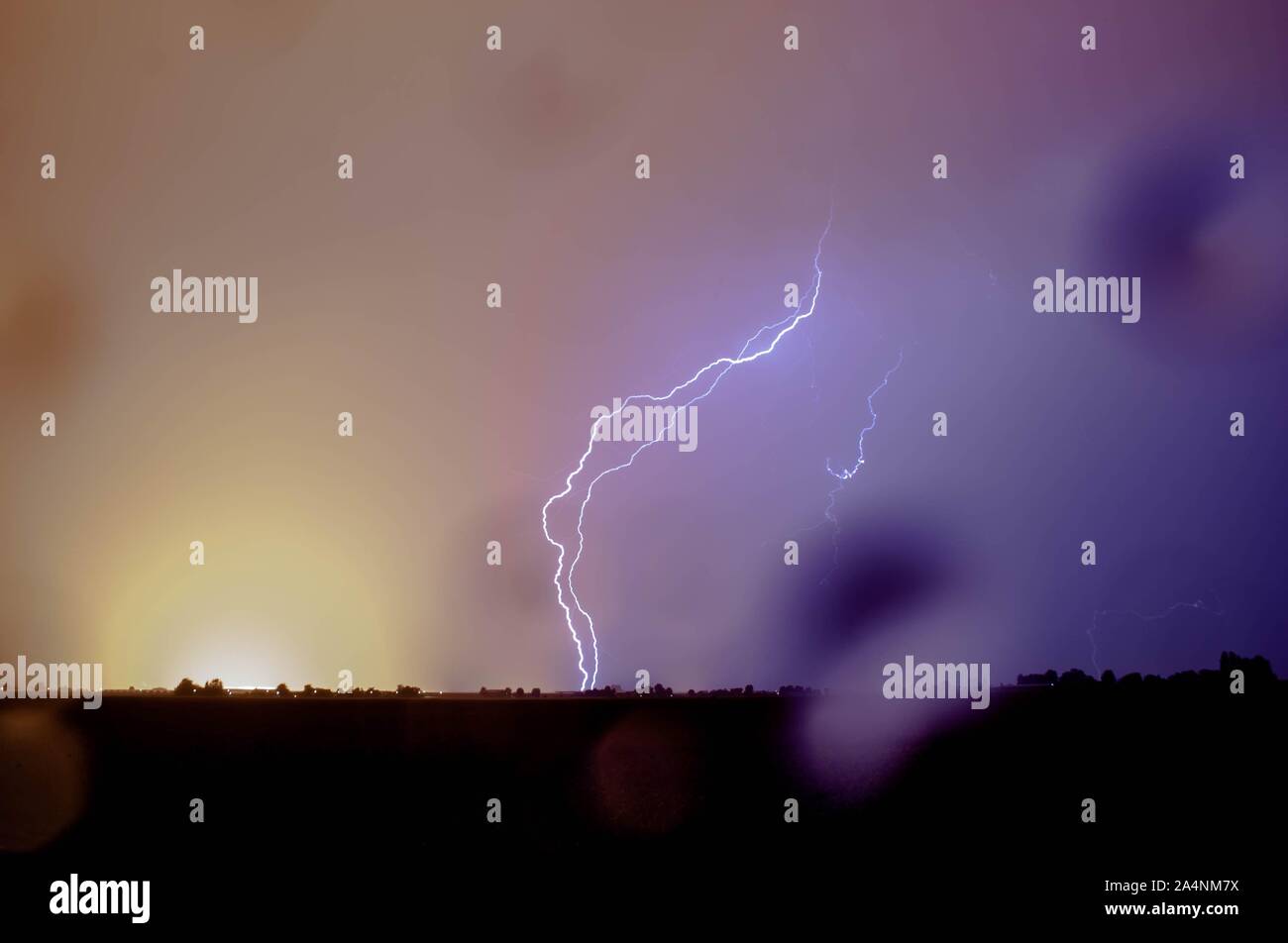 Doppel Blitzschlag trifft die Erde mit Regen während stürmisches Wetter. Regentropfen auf der Linse. Stockfoto
