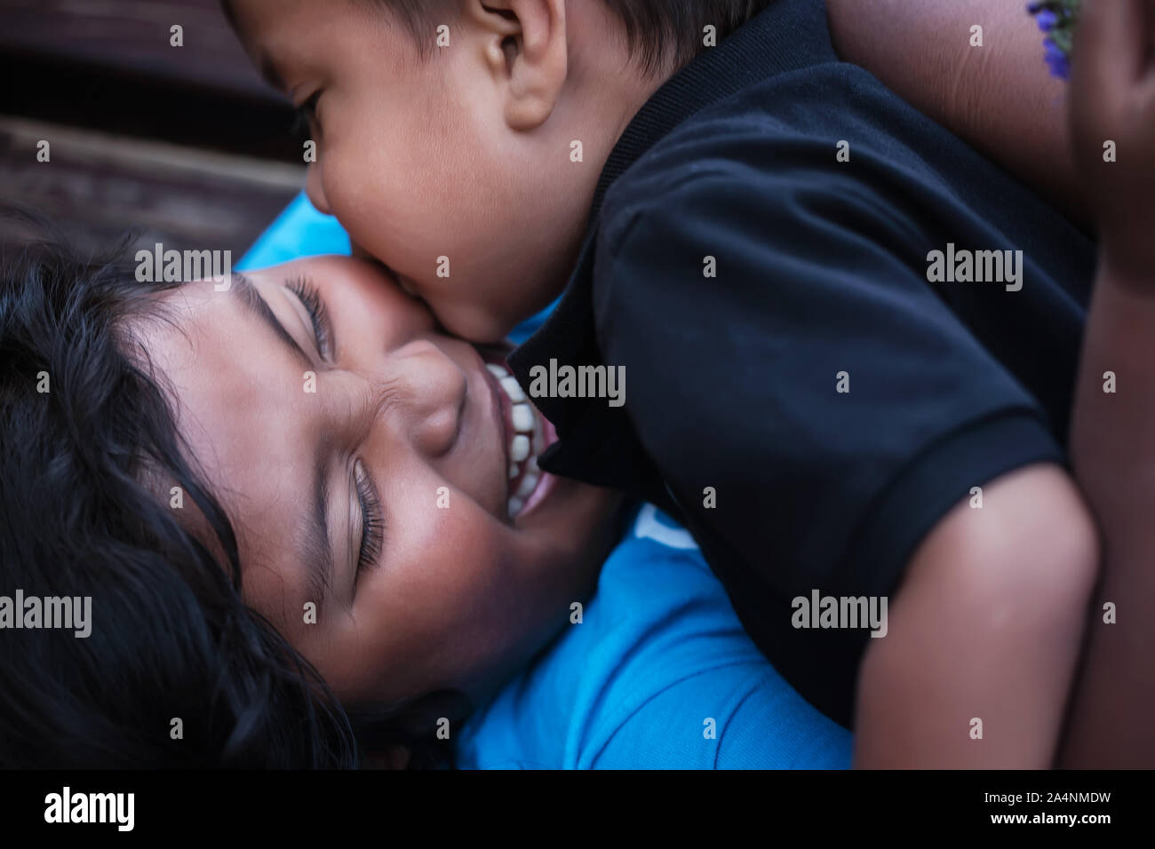 Einen kleinen Bruder gibt seine grosse Schwester einen Kuss auf die Wange, während Sie lacht laut in der Freude. Stockfoto
