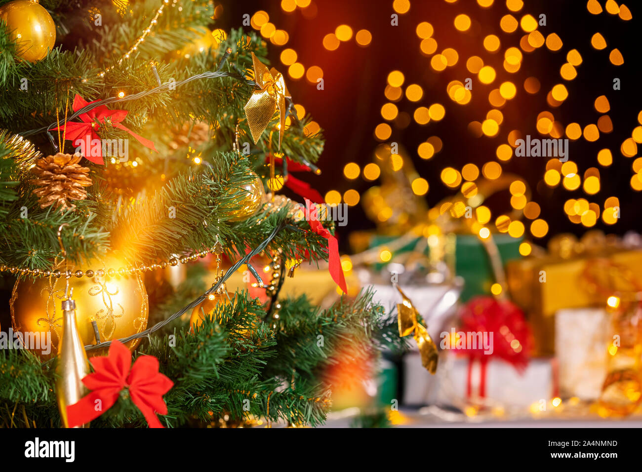 Stapel von Kisten verpackt Geschenk unter dem Weihnachtsbaum gegen Partikel leuchtet. Viele Weihnachten Geschenke unter dem Baum. Selektiver Fokus auf die gelbe Kugel! Stockfoto