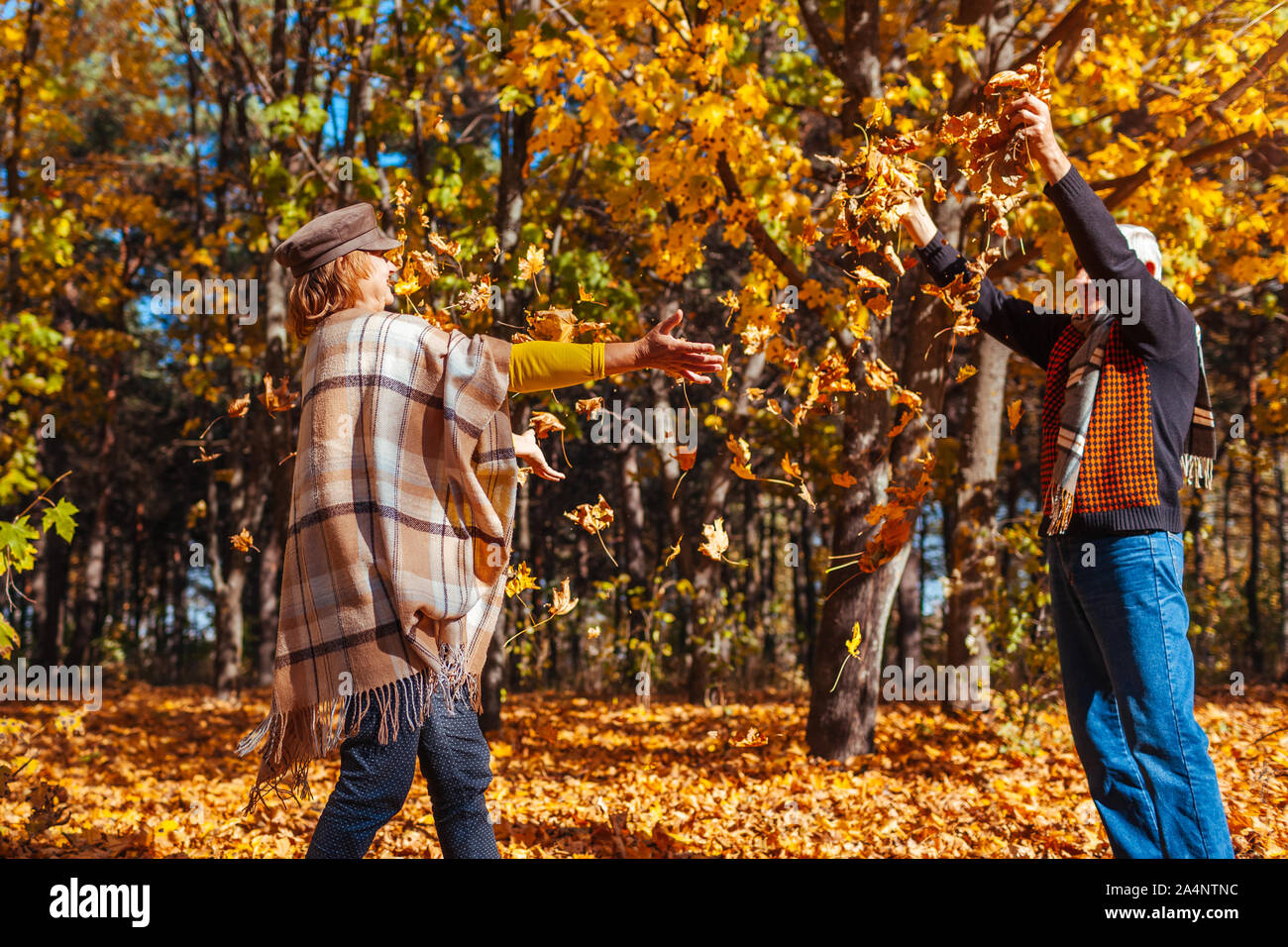 Herbst Jahreszeit. Paar Blätter im Herbst Wald werfen. Senior Familie Spaß im Freien Stockfoto