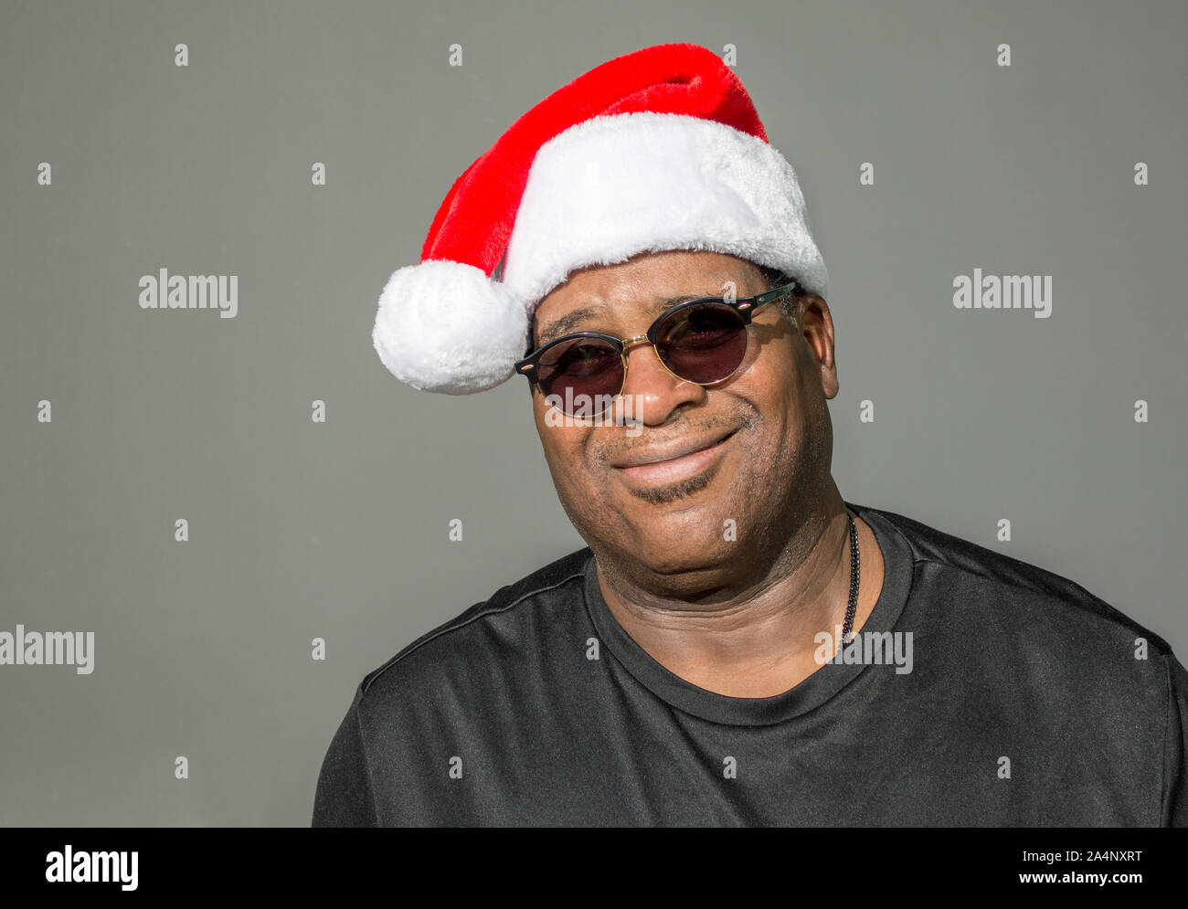 Lächelnd afrikanische amerikanische Mann im roten und weißen Santa Claus hat gegen einen soliden Hintergrund Stockfoto