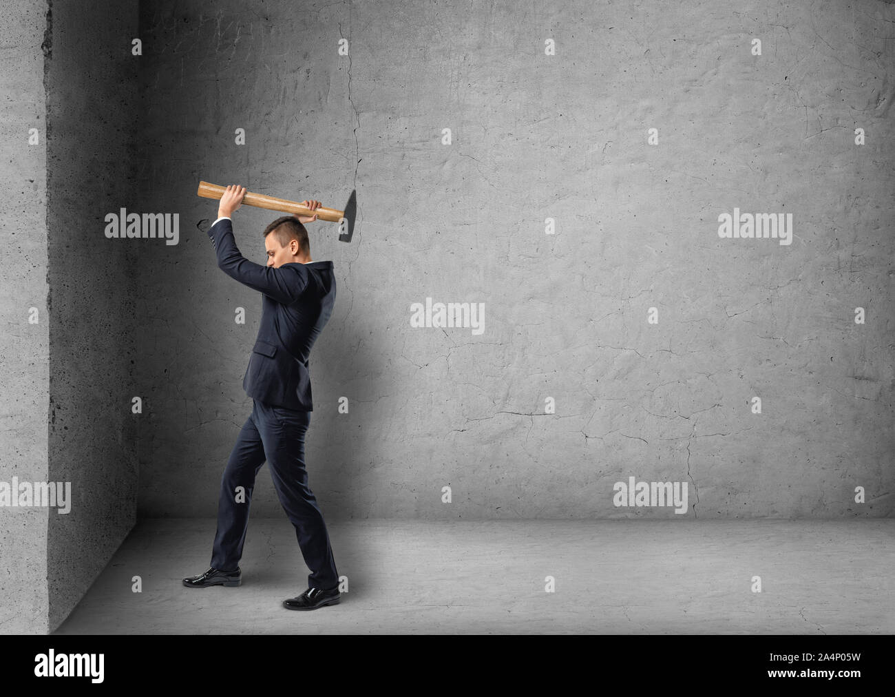 Seitenansicht eines Geschäftsmannes absturz Betonwand mit Hammer Stockfoto