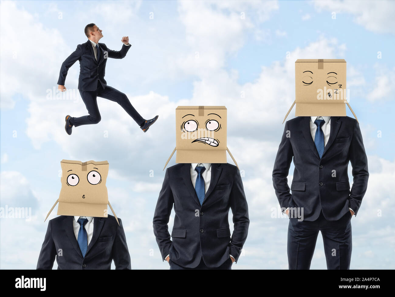 Kleine Unternehmer springen über drei Männer in Anzügen, die tragen Kartons mit bemalten Gesichtern. Stockfoto