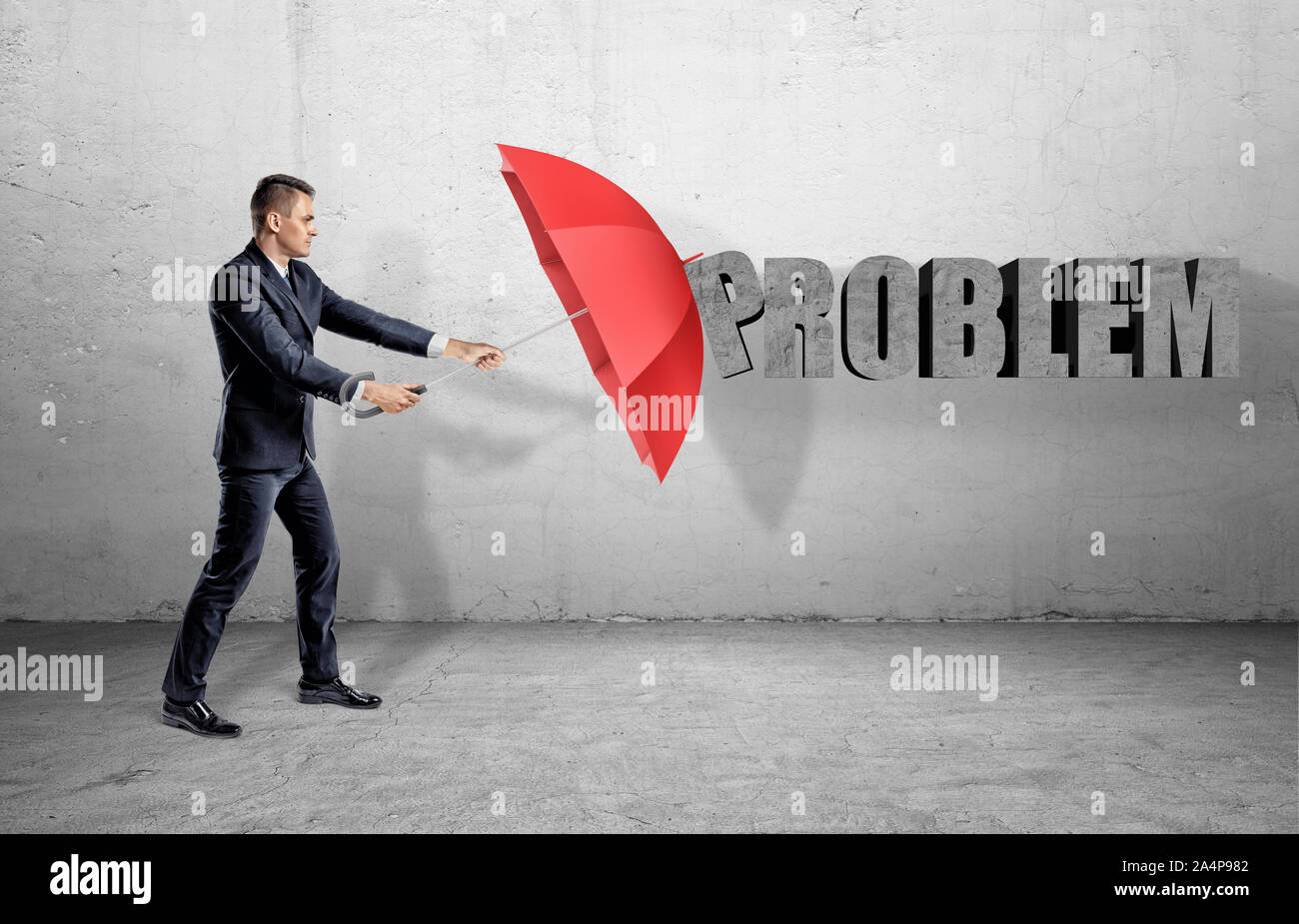 Ein Geschäftsmann, der sich hinter einem roten offenen Regenschirm von einem Wort "Problem" an der Wand. Stockfoto