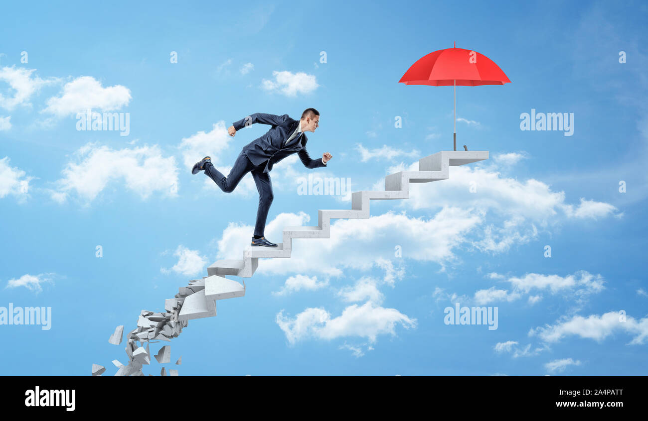 Ein Geschäftsmann mit bis auf Bröckelnden konkrete Schritte durch die Wolken einen roten Regenschirm zu erreichen. Stockfoto