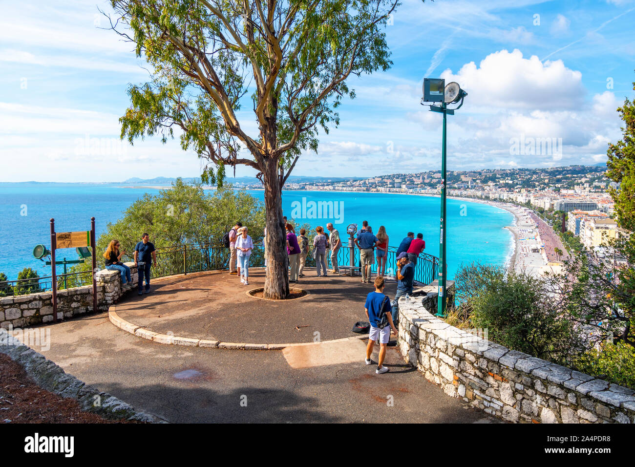 Eine Gruppe von Touristen und ein strassenmusiker versammeln sich auf einem Aussichtspunkt auf Castle Hill mit Blick auf Nizza Frankreich, die Bucht der Engel und der Französischen Riviera Beach Stockfoto