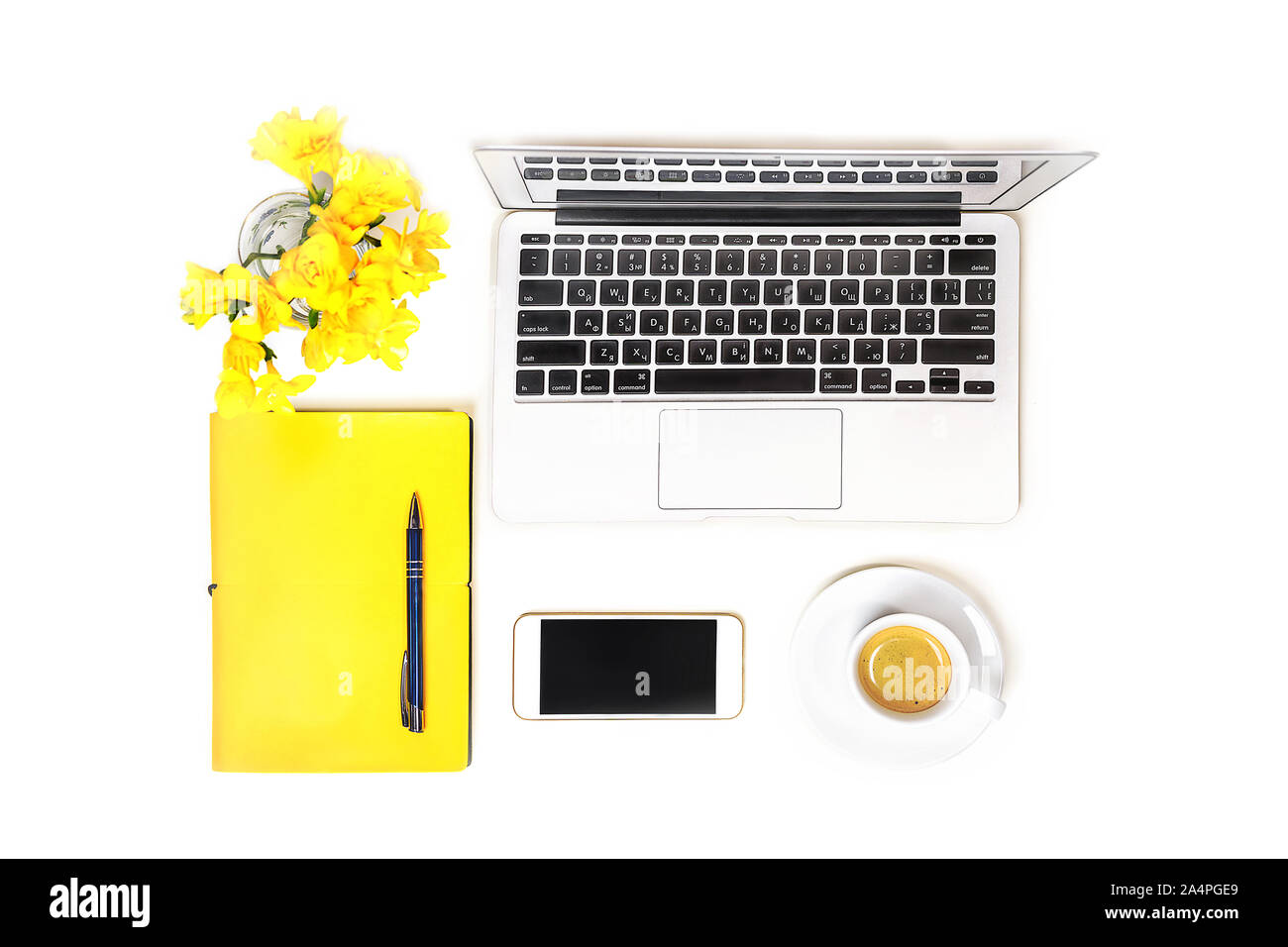 Arbeitsbereich mit Laptop, Tasse Kaffee, Mobiltelefon, Kopfhörer und gelbe Blume, Notizbuch mit Stift auf weißem Hintergrund, isoliert. Ansicht von oben. Flach. Konzept online einkaufen. Stockfoto